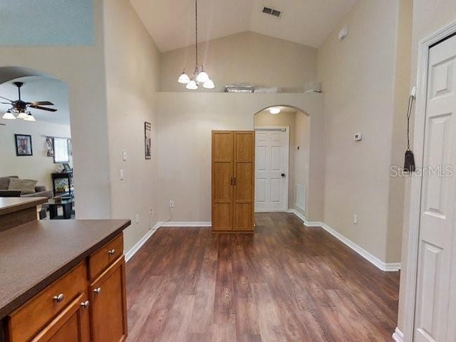 kitchen featuring pendant lighting, ceiling fan with notable chandelier, lofted ceiling, and dark wood-type flooring