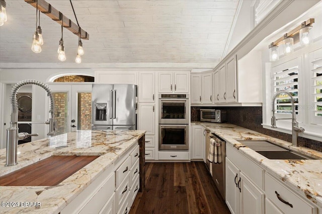 kitchen featuring pendant lighting, sink, light stone countertops, and stainless steel appliances