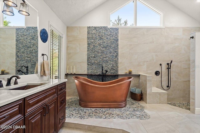 bathroom with vanity, tile walls, independent shower and bath, and vaulted ceiling