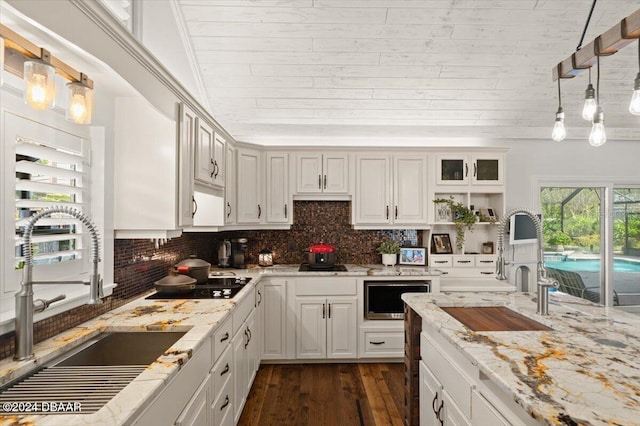 kitchen with decorative backsplash, sink, white cabinets, and pendant lighting