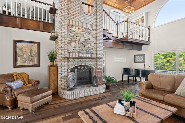 living room featuring dark hardwood / wood-style floors, a high ceiling, and a brick fireplace