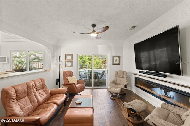 living room with hardwood / wood-style flooring, ceiling fan, and a textured ceiling