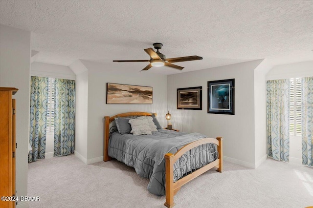 bedroom with a textured ceiling, light colored carpet, and ceiling fan