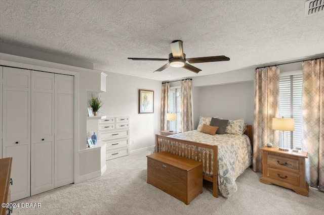 bedroom with multiple windows, ceiling fan, a closet, and light colored carpet