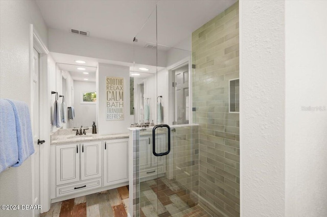 bathroom featuring hardwood / wood-style flooring, vanity, and a shower with shower door