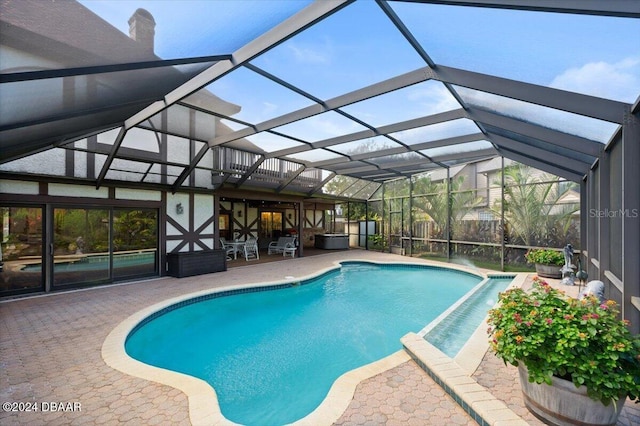 view of pool with glass enclosure and a patio area