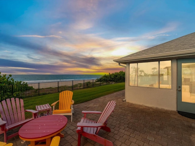 patio terrace at dusk with a yard and a water view