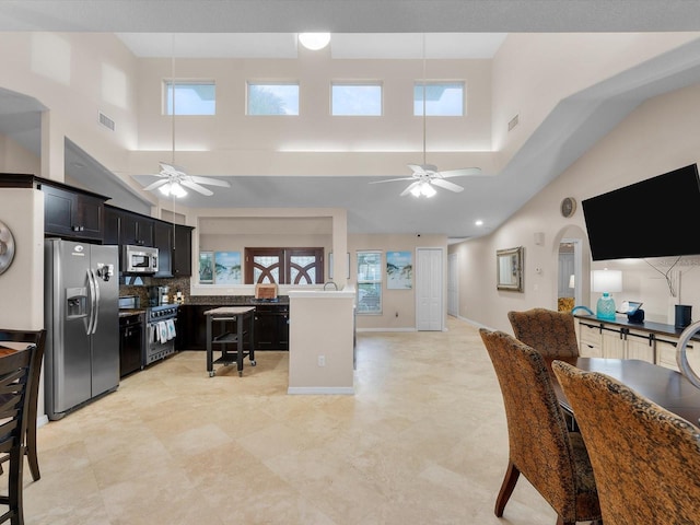 kitchen featuring a wealth of natural light, a towering ceiling, stainless steel appliances, and tasteful backsplash