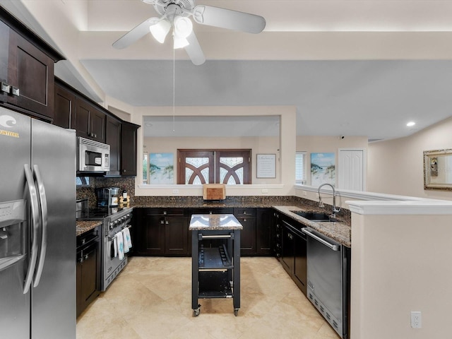 kitchen with a center island, dark stone counters, sink, dark brown cabinets, and stainless steel appliances