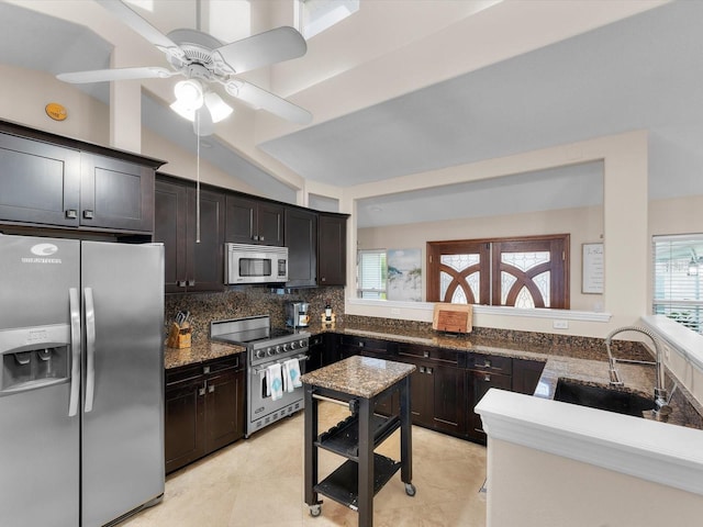 kitchen with sink, dark stone countertops, appliances with stainless steel finishes, tasteful backsplash, and dark brown cabinets