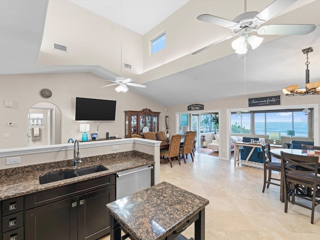 kitchen with decorative light fixtures, ceiling fan, dark stone countertops, and sink