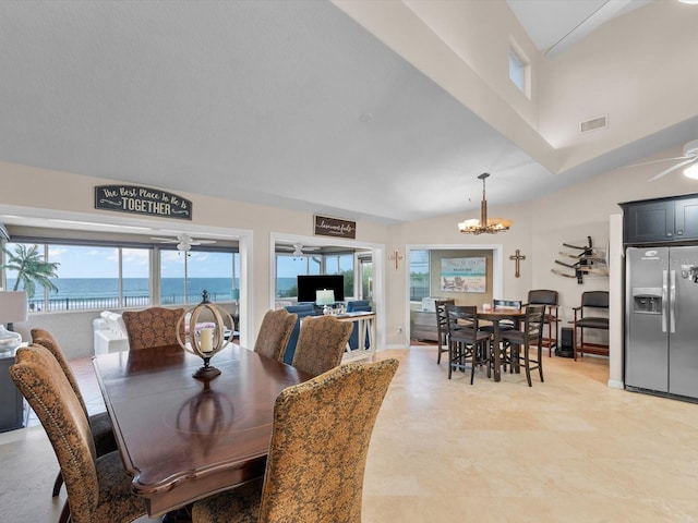 dining area with ceiling fan with notable chandelier and a water view