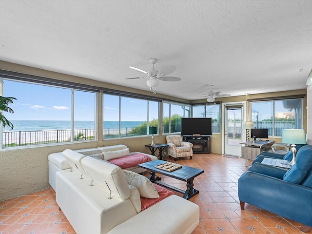 living room featuring tile patterned flooring, ceiling fan, and a water view