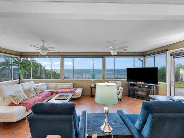 tiled living room featuring ceiling fan, a fireplace, and a healthy amount of sunlight