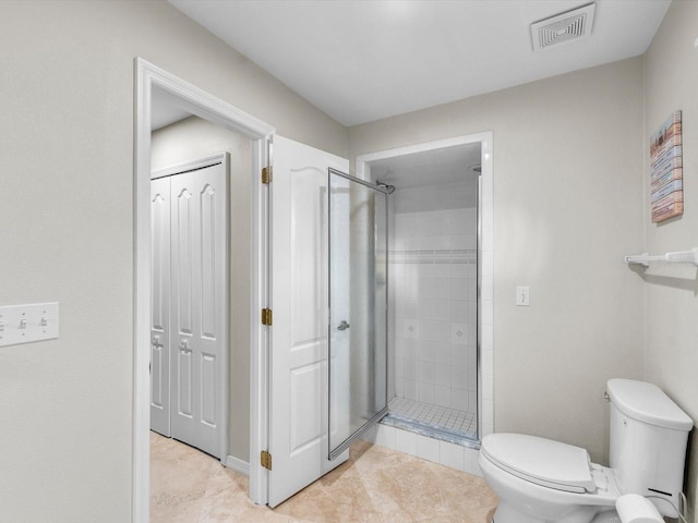 bathroom featuring tile patterned flooring, toilet, and walk in shower