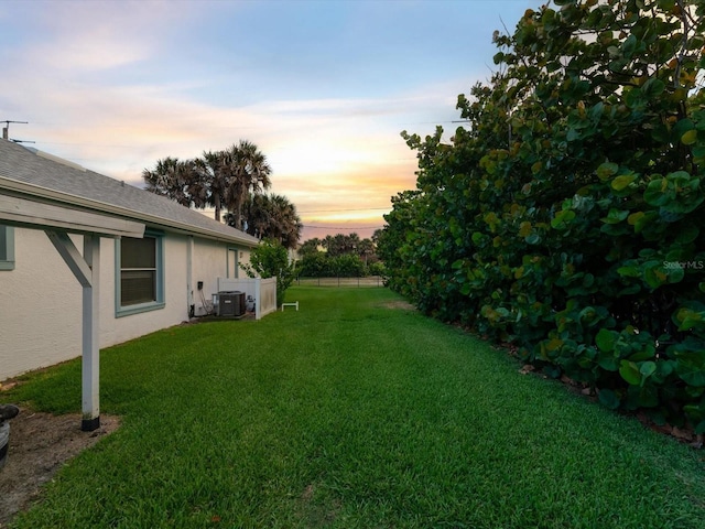 yard at dusk featuring central AC