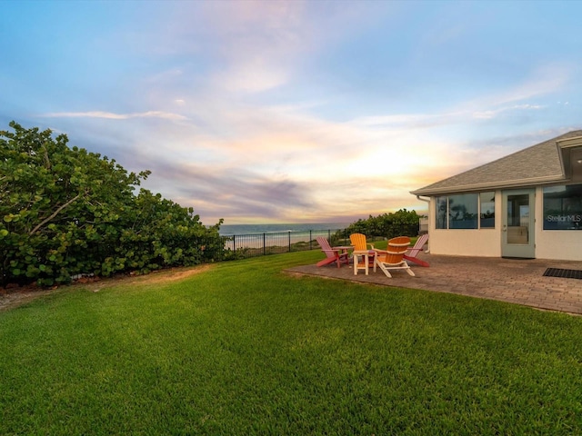 yard at dusk featuring a patio area and a water view