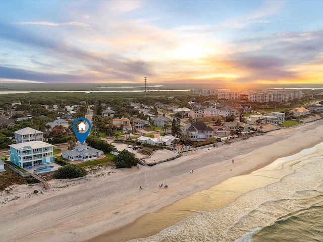 aerial view at dusk with a beach view and a water view