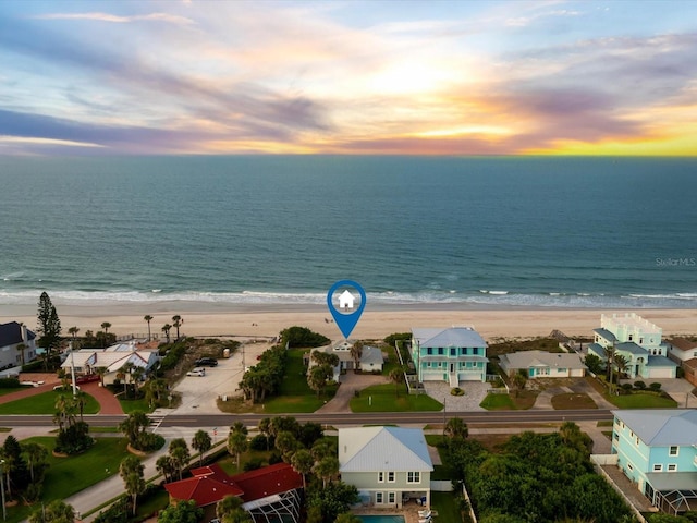 aerial view at dusk with a beach view and a water view