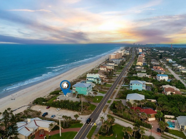 aerial view at dusk with a view of the beach and a water view