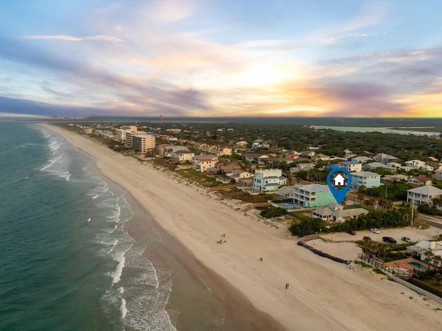 aerial view at dusk with a water view and a beach view