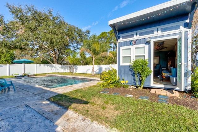 view of pool with a lawn, an outbuilding, and a patio