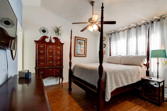 bedroom featuring a textured ceiling, dark hardwood / wood-style flooring, vaulted ceiling, and ceiling fan