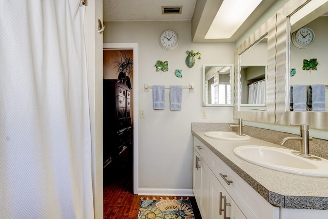 bathroom featuring hardwood / wood-style flooring, vanity, and a textured ceiling