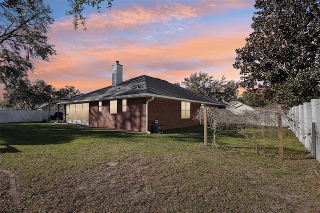 back house at dusk with a lawn