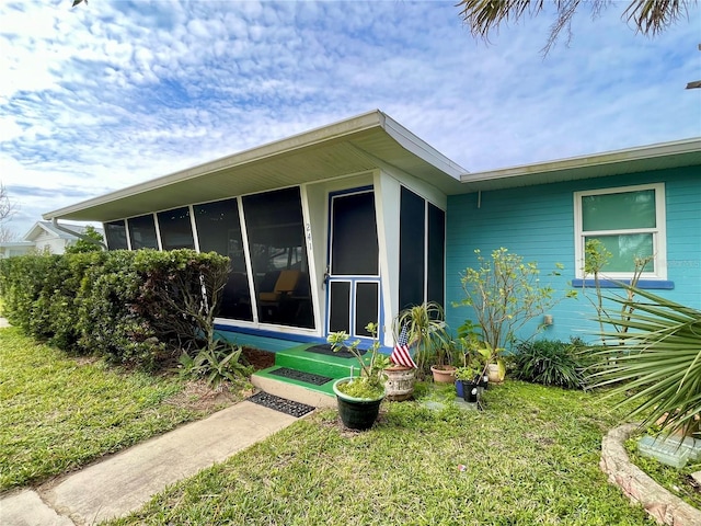 view of side of property featuring a sunroom and a yard