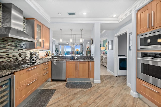 kitchen featuring kitchen peninsula, wall chimney exhaust hood, stainless steel appliances, pendant lighting, and wine cooler