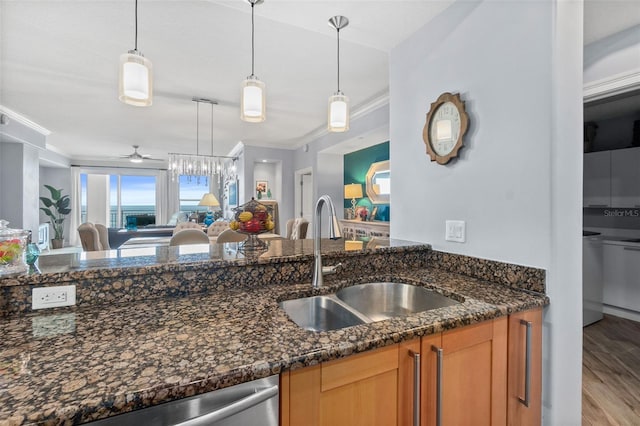 kitchen with decorative light fixtures, ceiling fan, dark stone counters, and sink