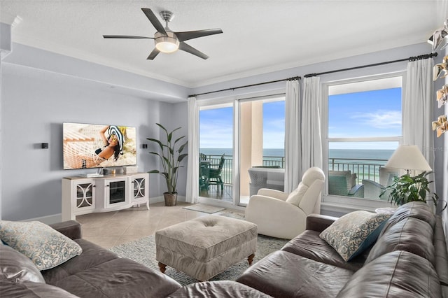 living room featuring ceiling fan, a water view, light tile patterned floors, and ornamental molding