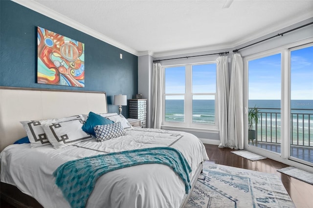 bedroom with access to exterior, hardwood / wood-style floors, a water view, and crown molding