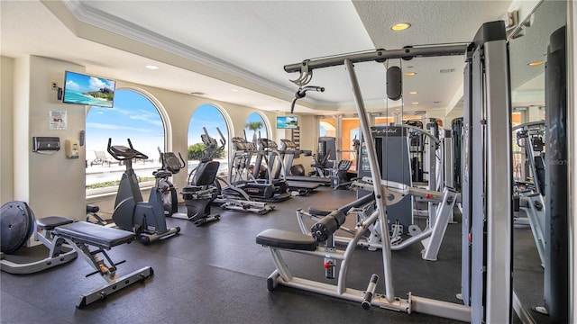 workout area featuring a tray ceiling, a textured ceiling, and ornamental molding