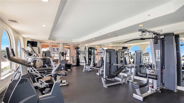 exercise room featuring a raised ceiling and ornamental molding