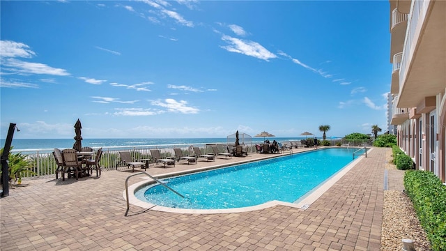 view of pool with a view of the beach, a water view, and a patio area