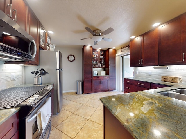 kitchen with stone counters, light tile patterned flooring, tasteful backsplash, and stainless steel appliances