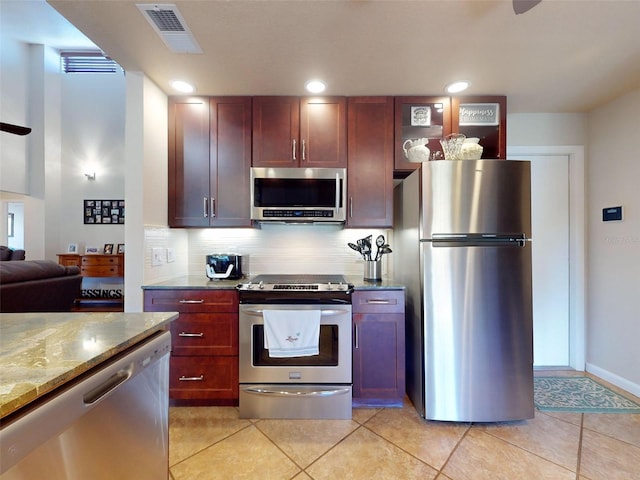 kitchen with appliances with stainless steel finishes, light stone countertops, decorative backsplash, and light tile patterned floors