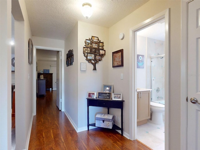 corridor with dark hardwood / wood-style floors and a textured ceiling