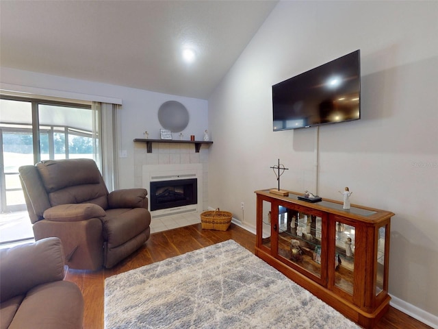 living room featuring lofted ceiling, dark hardwood / wood-style flooring, and a tiled fireplace