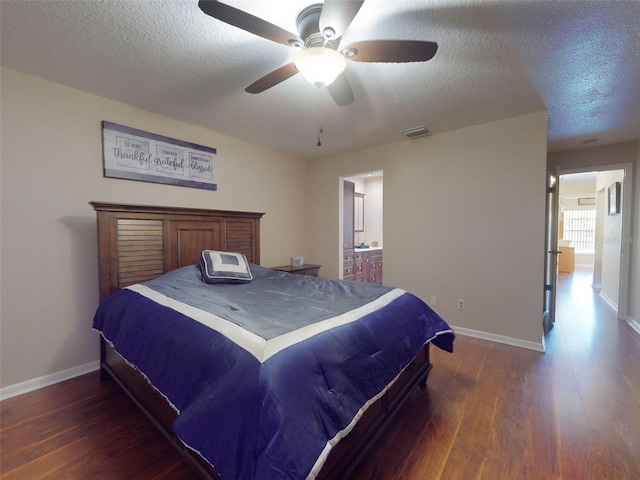 bedroom with dark hardwood / wood-style flooring, a textured ceiling, and ensuite bathroom