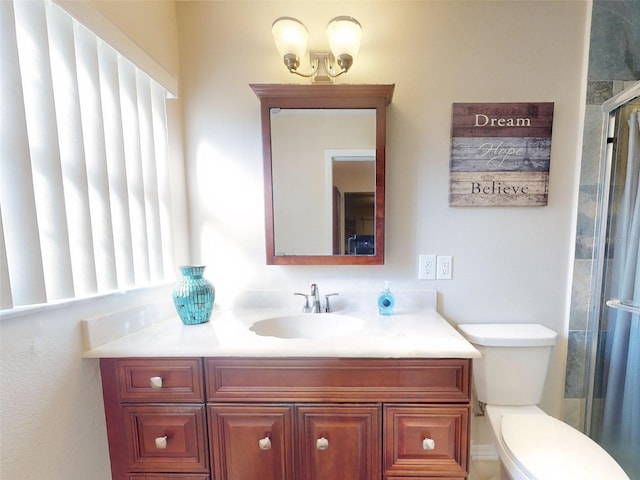 bathroom featuring vanity, a shower with door, toilet, and a healthy amount of sunlight