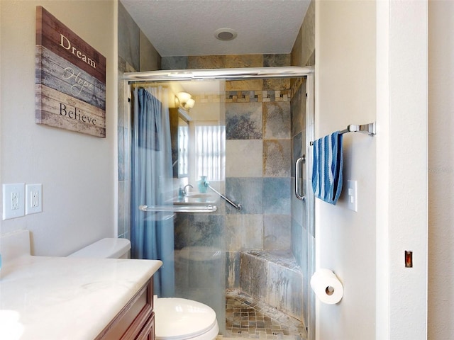 bathroom with a textured ceiling, vanity, toilet, and walk in shower