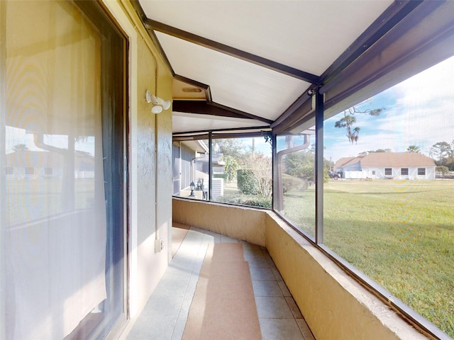 unfurnished sunroom featuring lofted ceiling with beams