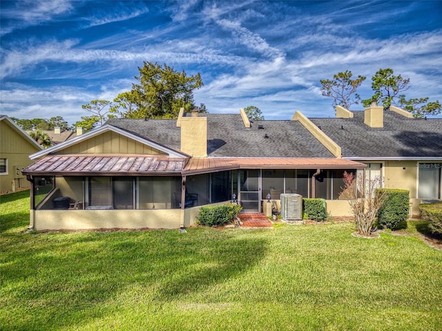 rear view of property featuring a sunroom and a lawn