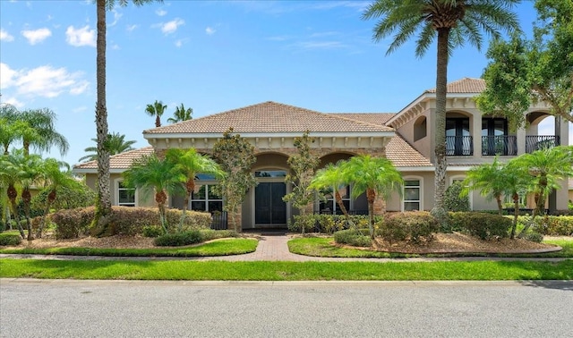 mediterranean / spanish-style house with a tiled roof, a balcony, and stucco siding