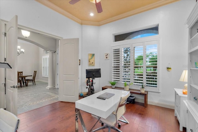 office space featuring arched walkways, crown molding, dark wood finished floors, ornate columns, and ceiling fan with notable chandelier