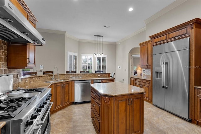 kitchen with stainless steel appliances, brown cabinets, a sink, and under cabinet range hood