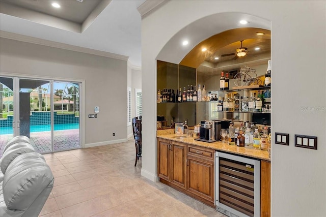 bar with a dry bar, wine cooler, baseboards, and a raised ceiling